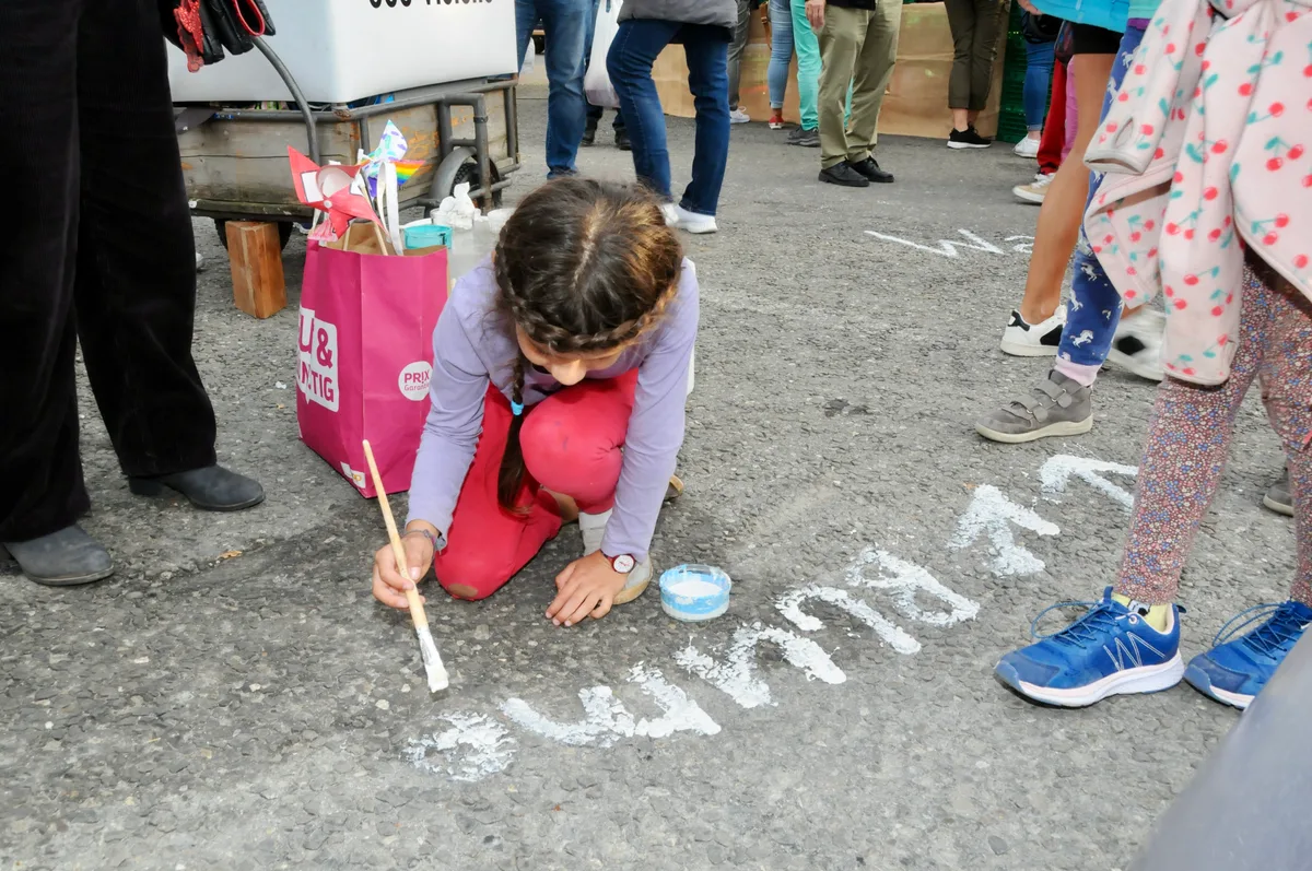 Man sieht ein Mädchen mit Farbe auf den Boden schreiben.